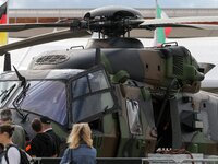 Visitors walk on the tarmac in front of  a NH 90 helicopter on the last day of the International Paris Air Show at Le Bourget Airport, near...