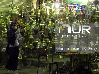 A muslim woman stands in front of a Ramadan lap street shop in Cairo on June 12, 2017 (