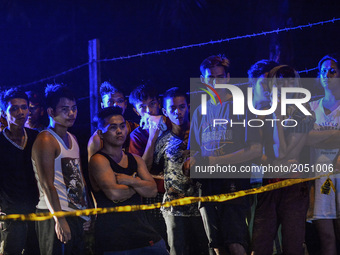Onlookers stand behind a police cordon near the scene where Irish Glorioso was shot dead by unknown assailants in Navotas, north of Manila,...