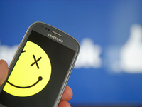 A smartphone with a smiley symbol is seen with the Facebook logo in the background in this photo illustration on 29 June, 2017, in Bydgoszcz...
