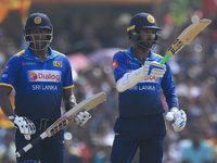 Sri Lankan cricket captain Angelo Mathews(L) looks on as Upul Tharanga (R) raises his bat after scoring 50 runs during the 2nd One Day Inter...