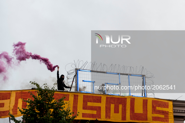 A Woman holds a smoke grenade beside a G20 neon sign on the roof of the autonomous center Rote Flora in the air. About 20000 people demonstr...