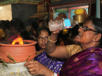 Tamil Hindu woman pours water on her face to combat the heat as she carries a clay pot with flaming camphor as part of the rituals during th...