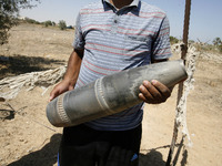 A Palestinian man holds a the Projectile fired from an Israeli fly earlier in Rafah in the southern Gaza Strip, on August 6, 2014, while Isr...
