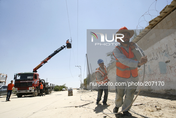 Palestinian electricity company workers drag a power line many of which were destroyed following an earlier Israeli air strike in Rafah in t...