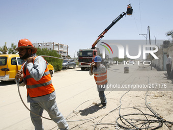 Palestinian electricity company workers drag a power line many of which were destroyed following an earlier Israeli air strike in Rafah in t...