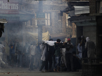 kashmiri people carrying the body of  local pro-independence fighter  Sajad Ahmed Gilkar  as they make there way through Tear smoke fired by...