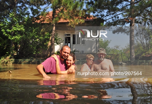 Family pose for a picture in front of their flooded home and try to save belongings, animals and pets in the flooded town of Mizia north-eas...