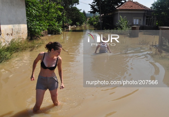 Family pose for a picture in front of their flooded home and try to save belongings, animals and pets in the flooded town of Mizia north-eas...