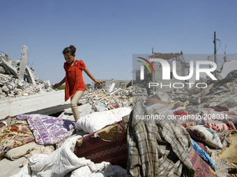 A Palestinian girl inspects the rubble of their destroyed home following an Israeli air strike on Abasan, east of the southern Gaza Strip to...