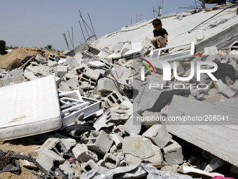 A Palestinian child sits on the rubble of a house which was destroyed in an Israeli air strike on Abasan, east of the southern Gaza Strip to...