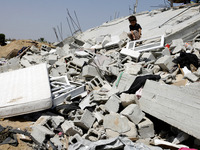 A Palestinian child sits on the rubble of a house which was destroyed in an Israeli air strike on Abasan, east of the southern Gaza Strip to...