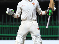 Zimbabwe's Sikandar Raza looks up to the sky and reacts after scoring fifty runs during the third day's play of the only test cricket match...