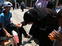 A Palestinian woman drinks water to cool off during a demonstration against the siege of Gaza and in solidarity with Al-Aqsa Mosque, in Gaza...