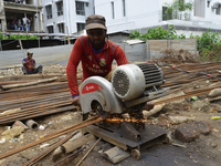 Bangladeshi worker cutting iron sticks at a building construction site in Dhaka, Bangladesh, on July 18, 2017   (