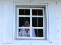 A lady looks by a window of a house built in the second half of the 19th century, in the Folk Culture Open-Air Museum in Kolbuszowa. 
On Sun...