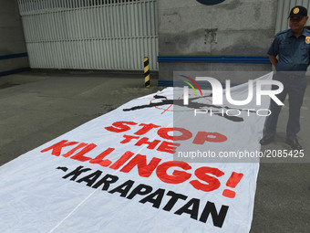 A police officer looks on as protesters laid out their banner in front of the gates of Camp Crame, the national headquarters of the Philippi...