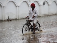 A men cross flood waters street after heavy rains in Pushkar, India, on August 8, 2014. (
