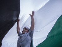 A Palestinian kids holds a giant Palestinian flag during a protest outside U.S. Embassy in Kuala Lumpur, Malaysia on Friday, July 21, 2017....