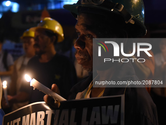 Workers joined by protesters from different groups light candles in front of the gates of the presidential palace in Manila on 21 July 2017....
