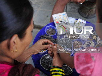 A Mother select ring to her child during Gathemangal festival in Kathmandu, Nepal on Friday, July 21, 2017. People wear metal rings to safeg...