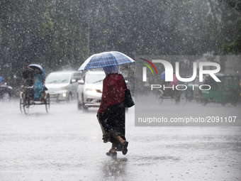 Woman with umbrella walk in the street when heavy rainfall maid in the Dhaka, Bangladesh on July 23, 2017. (
