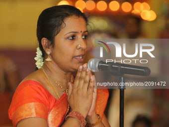 Tamil Hindu woman sings a devotional prayer honouring Lord Ganesh during the Nambiyaandaar Nambi Ustavam Thiruvizha pooja at a Hindu Temple...