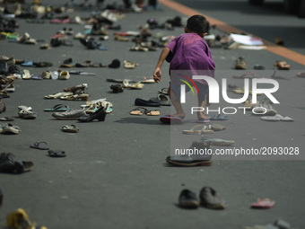 A child picks up a pair of slippers as a protest group placed an art installation comprising various types of footwear to symbolize the vict...