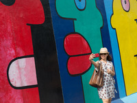 Visitors walk along the East Side Gallery, a mile-long section of the Berlin Wall still standing that is covered in murals and graffiti, on...