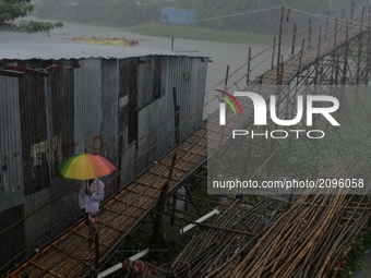 Man is crossing a wooden bridgeduring  a heavy rainfall in , Dhaka, Bangladeshon Wednesday, 26, july, 2017. Moderate to heavy rainfall have...