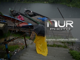 A boatman holding an umbrella during a heavy rainfall in Dhaka , Bangladesh on wednesday, 26, July, 2017.Moderate to heavy rainfall have bee...