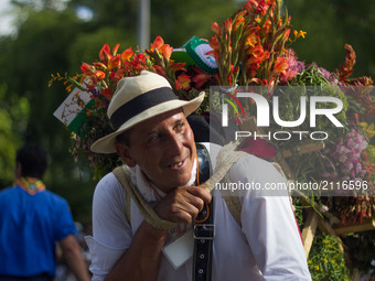 A man carries flowers with the wooden crate in his back during the last day of the Festival of the Flowers at Guayabal avenue in Medellin, C...