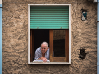 An elderly man looks out the window his apartment in Caronia, Sicily, Italy, on 16 August 2015. (