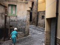An elderly woman walks in the streets of Caronia, Sicily, Italy on 16 August 2015. (