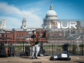 A pusker is pictured while he performs, against the backdrop of St. Paul's Cathedral, in a sunny morning in the Southbank of London, on Augu...