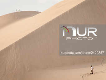 A tourist checks his phone on sand dunes in a desert near Huacachina, Peru. Photo taken 4 April 2012. (