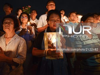Thai people hold up pictures Thai King Maha Vajiralongkorn and lights candle his celebrate of Queens Sirikit birthday in Bangkok, Thailand,...