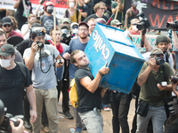 A counter protester prepares to throw a newspaper box at white supremacists in Emancipation (Lee) Park in Charlottesville, Virginia on Augus...