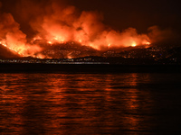 Massive wildfire with multiple front burning houses at Kalamos Attika, scene shot from a distance of 5 km in Amarynthos, Eretria on Euboea o...