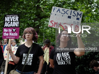 People gather to stage a demonstration as they hold placards during the 'Stand up to Racism' protest outside the US Embassy in London on Aug...