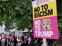People gather to stage a demonstration as they hold placards during the 'Stand up to Racism' protest outside the US Embassy in London on Aug...