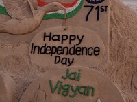 Visitors look near to the Independence Day sand sculpture, creating by sand artist Sudarshan Patnaik at the Bay of Bengal Sea's eastern coas...
