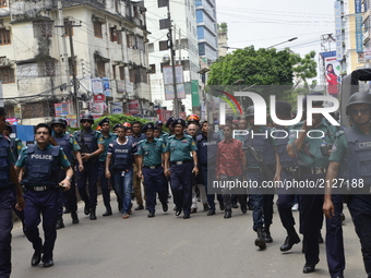 Bangladesh police officials stand guard as bystanders gather at the scene of an operation to storm an alleged militant hideout in Dhaka on A...