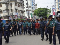 Bangladesh police officials stand guard as bystanders gather at the scene of an operation to storm an alleged militant hideout in Dhaka on A...