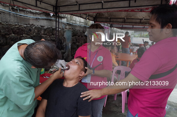A dentist performs a tooth extraction to a patient during a medical mission at a village in Quezon City, east of Manila, Philippines on Sund...