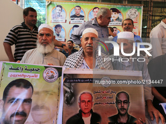 Palestinian families hold posters of their relatives as they gather for a demonstration to show their support for the Palestinian prisoners...