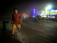 NEW YORK. A man looking to find the nearest shelter as the wind and sand hits the residents along the Coney Island boardwalk on Tuesday, Jul...