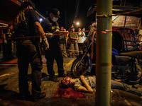 Police investigators inspect the body of a man who was killed by an unknown assailant in Mandaluyong, Metro Manila, Philippines, August 19,...