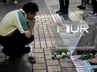 A man prays on the photo of Heather Heyer during the standing silent appeal, a hundred people gathered in shibuya against racism and violenc...