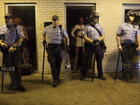 Ferguson Police wait by shops along W. Florissant Ave in Ferguson, during a protest for the killing of teenager Michael Brown on August 17,...
